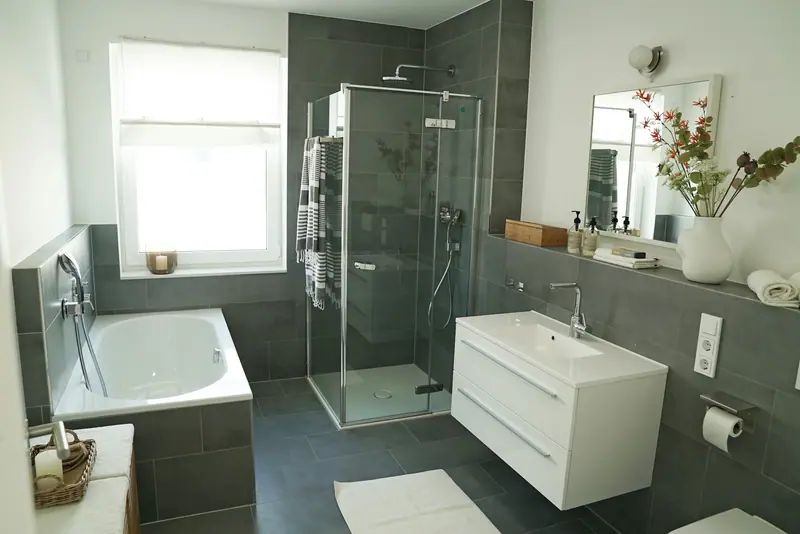 Afgewerkte gezinsbadkamer met ligbad, glazen douchecabine en wastafelmeubel